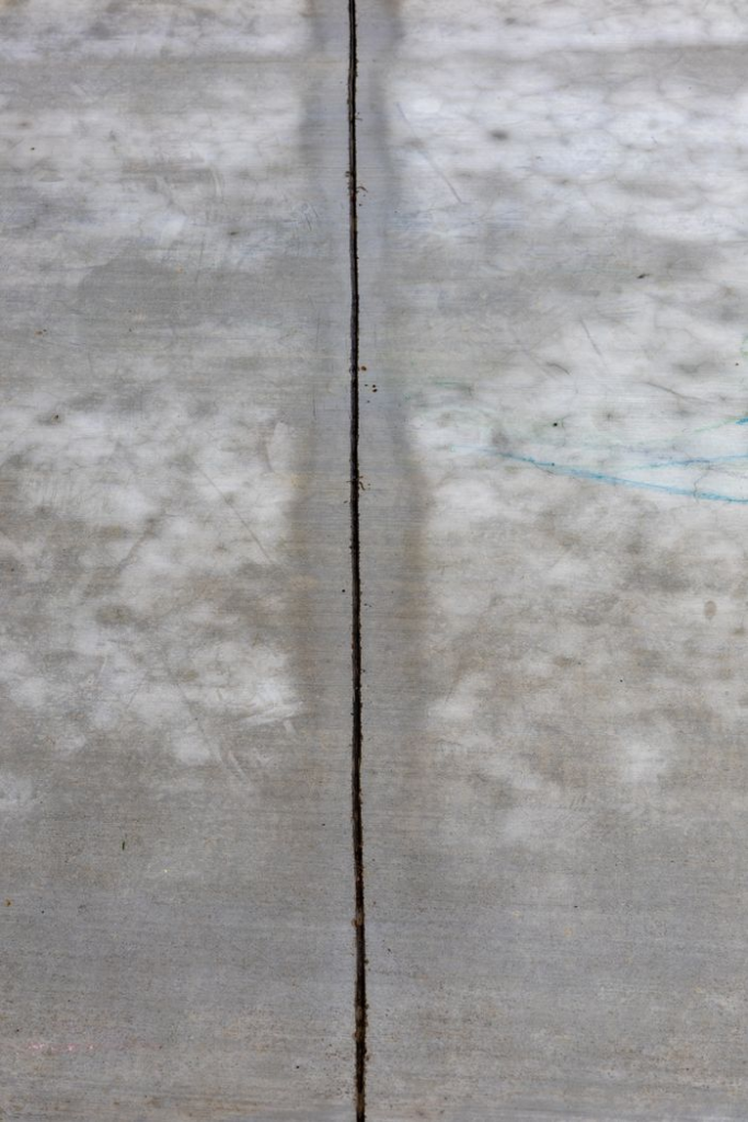 Detailed view of a cracked concrete surface, emphasizing texture and line.